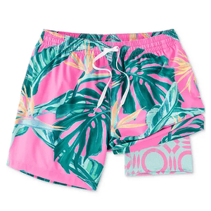 Pink swim trunks with a tropical leaf pattern in green and yellow, featuring an elastic waistband and white drawstring.