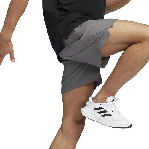 A person wearing grey athletic shorts and white sneakers with black stripes.