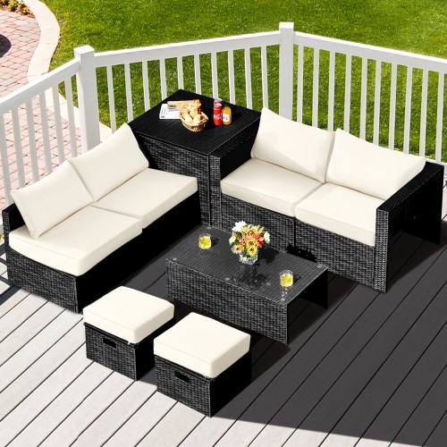 Outdoor patio set with black wicker and white cushions, including a corner sofa, two stools, and a coffee table topped with a flower vase, placed on a wooden deck.