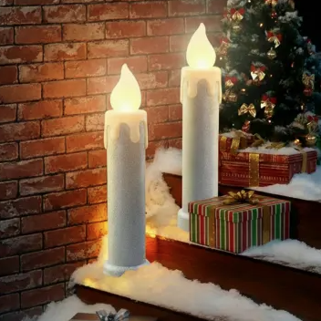 Oversized LED candle decorations on snowy steps, surrounded by wrapped gift boxes and a decorated Christmas tree in the background.