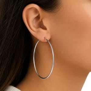 Close-up of a person wearing a large, thin metallic hoop earring.