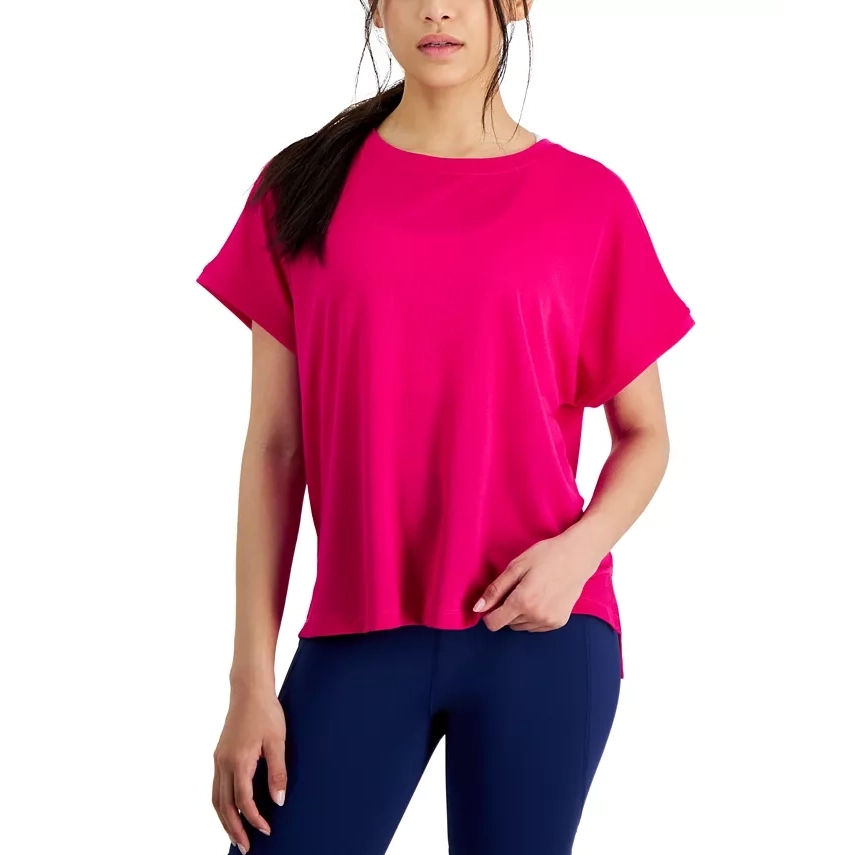A woman is wearing a bright pink, short-sleeved, loose-fitting blouse and navy blue leggings.