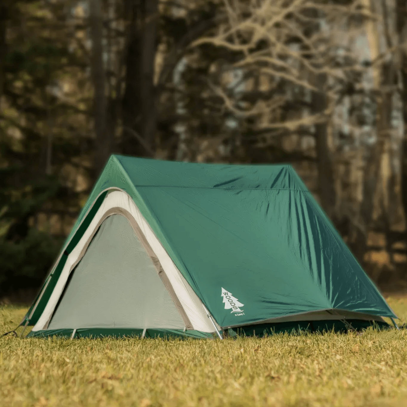 A green A-frame tent on a grassy field, suitable for camping with a simple, classic design and reinforced seams for durability.
