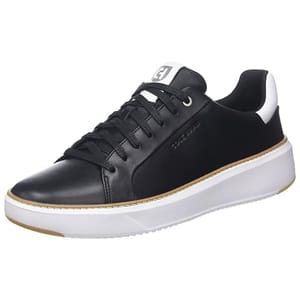 The Cole Haan Grandpro Topspin Sneaker for men features a sleek black leather upper with white detailing, lace-up closure, and a lightweight white sole. Embossed branding adds a subtle touch.