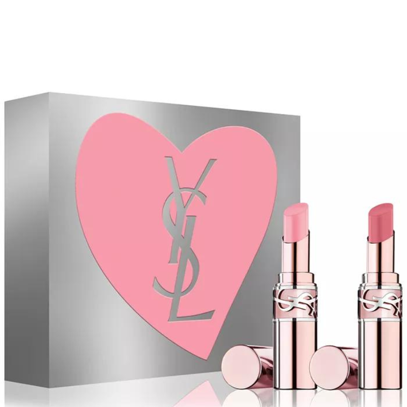 Two Yves Saint Laurent (YSL) lip balms with silver and pink packaging are displayed in front of a silver box with a pink heart and the YSL logo.
