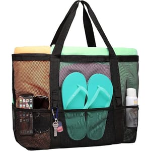 A black mesh tote bag holding towels, turquoise flip-flops, sunscreen, a smartphone, sunglasses, and keys with an American flag keychain.