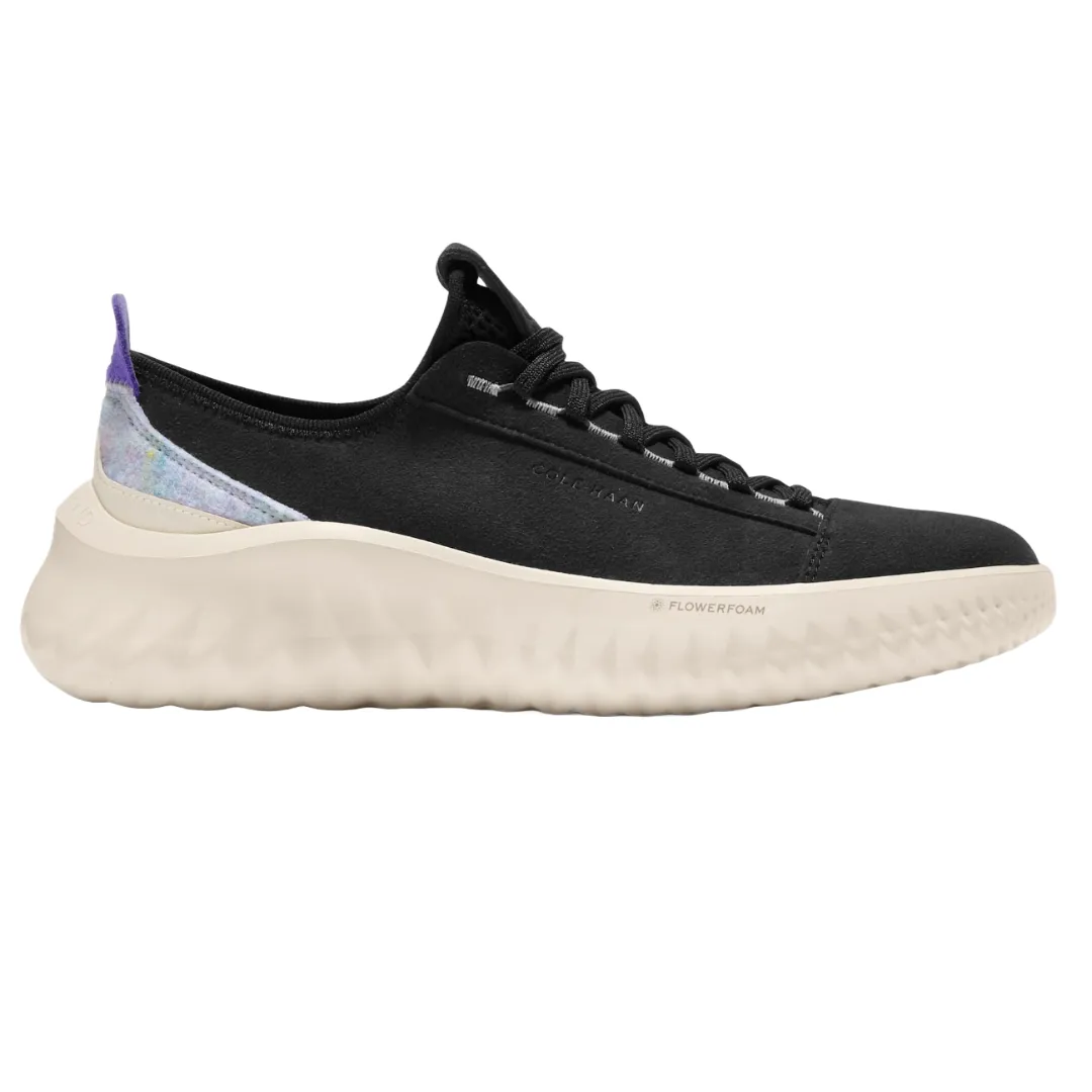 Cole Haan ZeroGrand II Sneakers feature a sleek black upper with black laces and a thick, textured white sole. The design includes a colorful detail near the heel and \“FLOWERFOAM\“ branding on the sole.