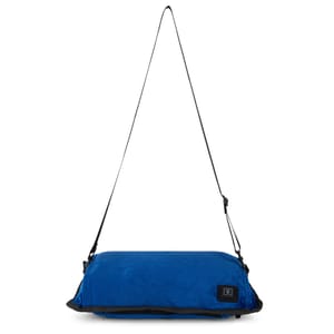 A blue, rectangular hand warmer pillow with a soft texture, featuring an adjustable black shoulder strap and a small, visible logo patch.