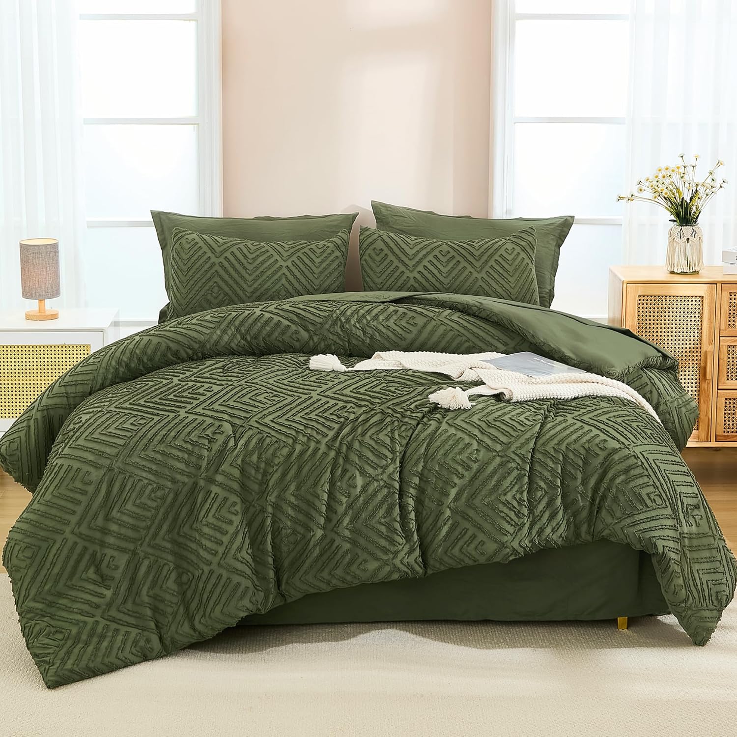 Green geometric-patterned comforter set with matching pillow shams on a bed, featuring a white lamp and floral arrangement on side tables.