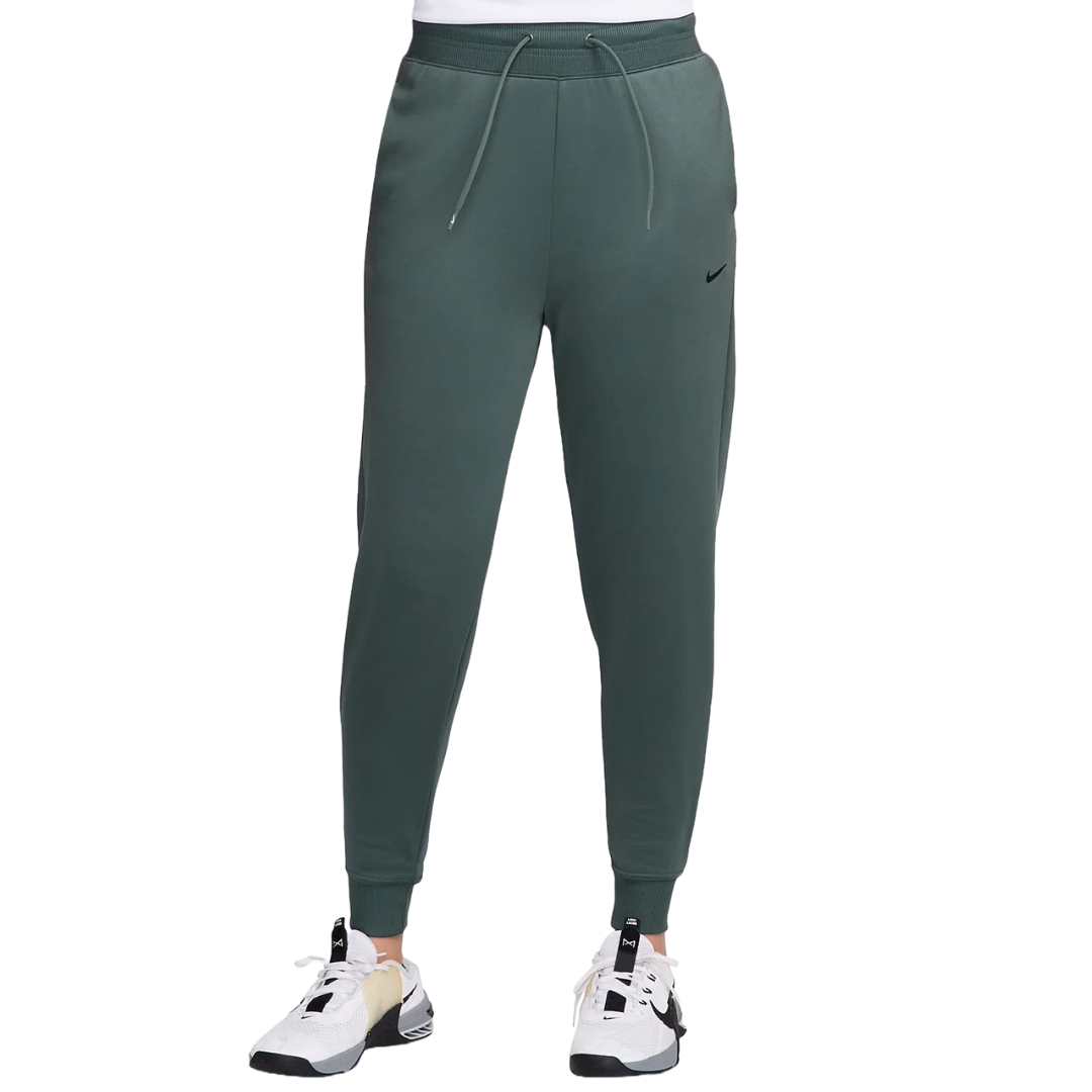 Nike Women's Therma-FIT Jogger Pants are dark green with a slim fit, featuring an elastic waistband, adjustable drawcord, cuffed ankles, and a small black swoosh logo. They are paired with white and black sneakers.