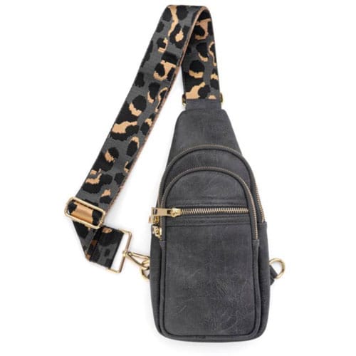 A black sling bag with multiple zippered compartments and a leopard-print adjustable strap.