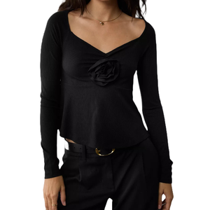 A long-sleeve black babydoll shirt with a sweetheart neckline and a decorative rose detail at the center. The fit is slightly flared at the waist, paired with black pants and a belt with a round gold buckle.