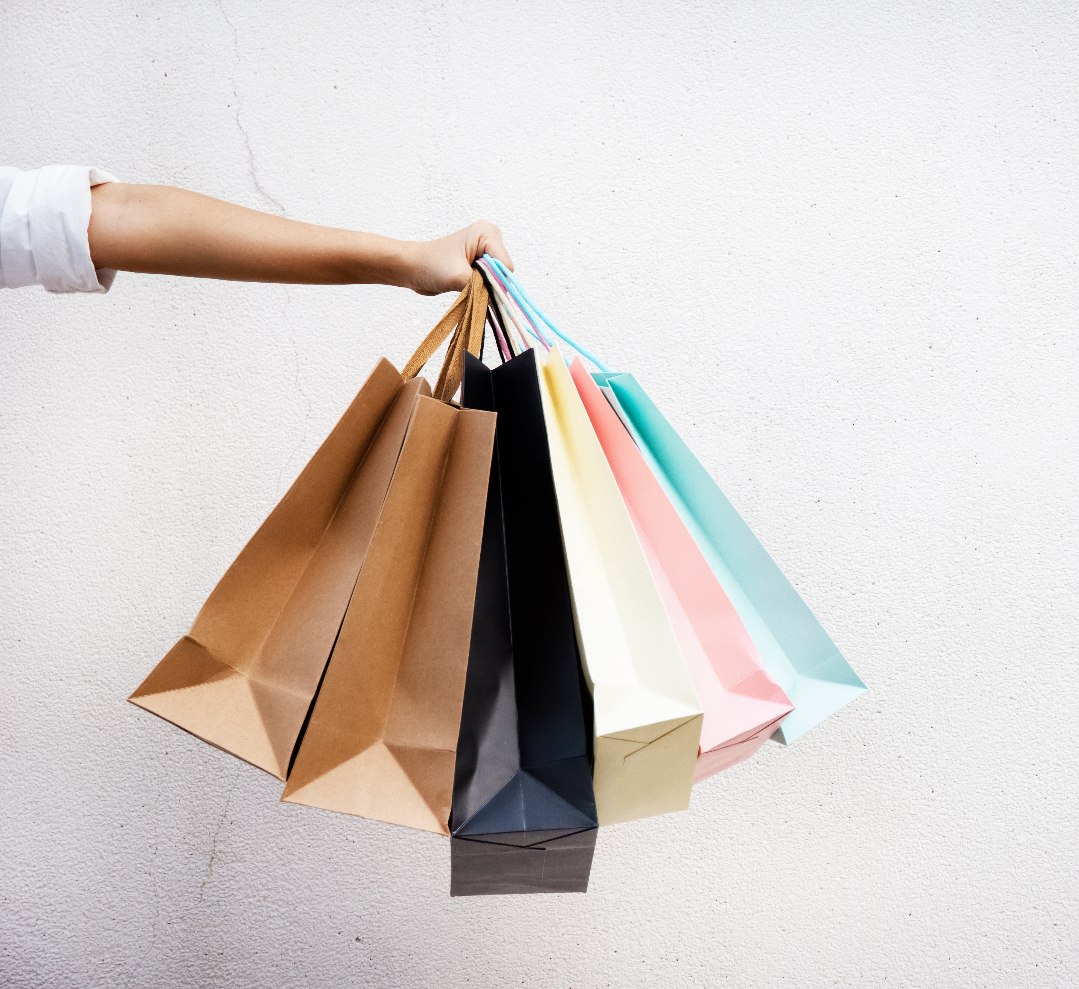 A person is holding several colorful shopping bags.