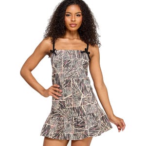 Sleeveless dress with a geometric pattern featuring black straps with small bows and a ruffled hemline.