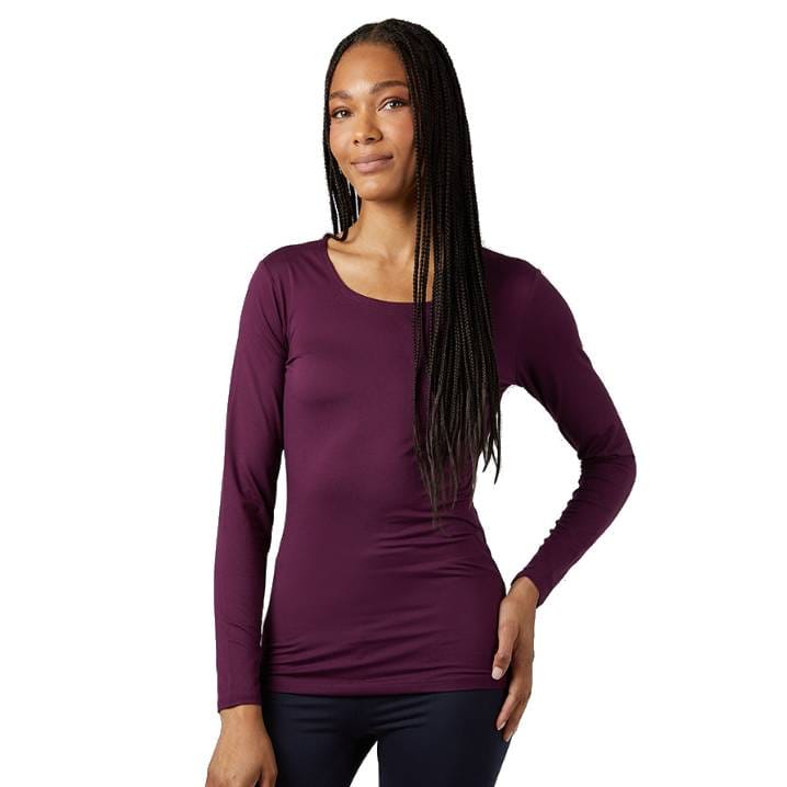 A woman is wearing a long-sleeve, dark purple top paired with dark pants. She has long braided hair and is standing against a white background.