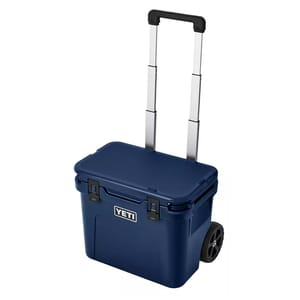 A YETI wheeled cooler with a telescopic handle in blue, designed for easy transport and cold storage on the go.