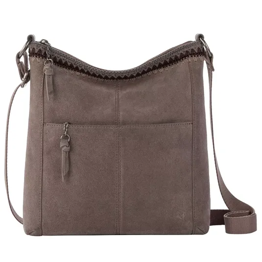 A taupe suede crossbody bag featuring a zippered front pocket, curved top with crochet detailing, and an adjustable strap.