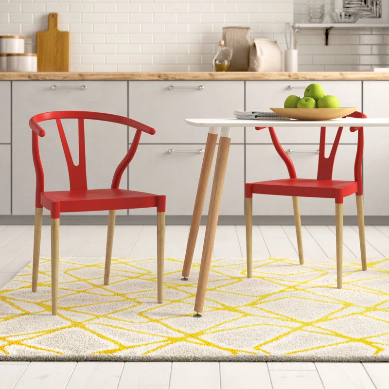 The 2pc Slatted Back Armchair Set features two red chairs with curved backs and slatted designs. They have wooden legs and complement a modern aesthetic, ideal for dining or kitchen spaces.