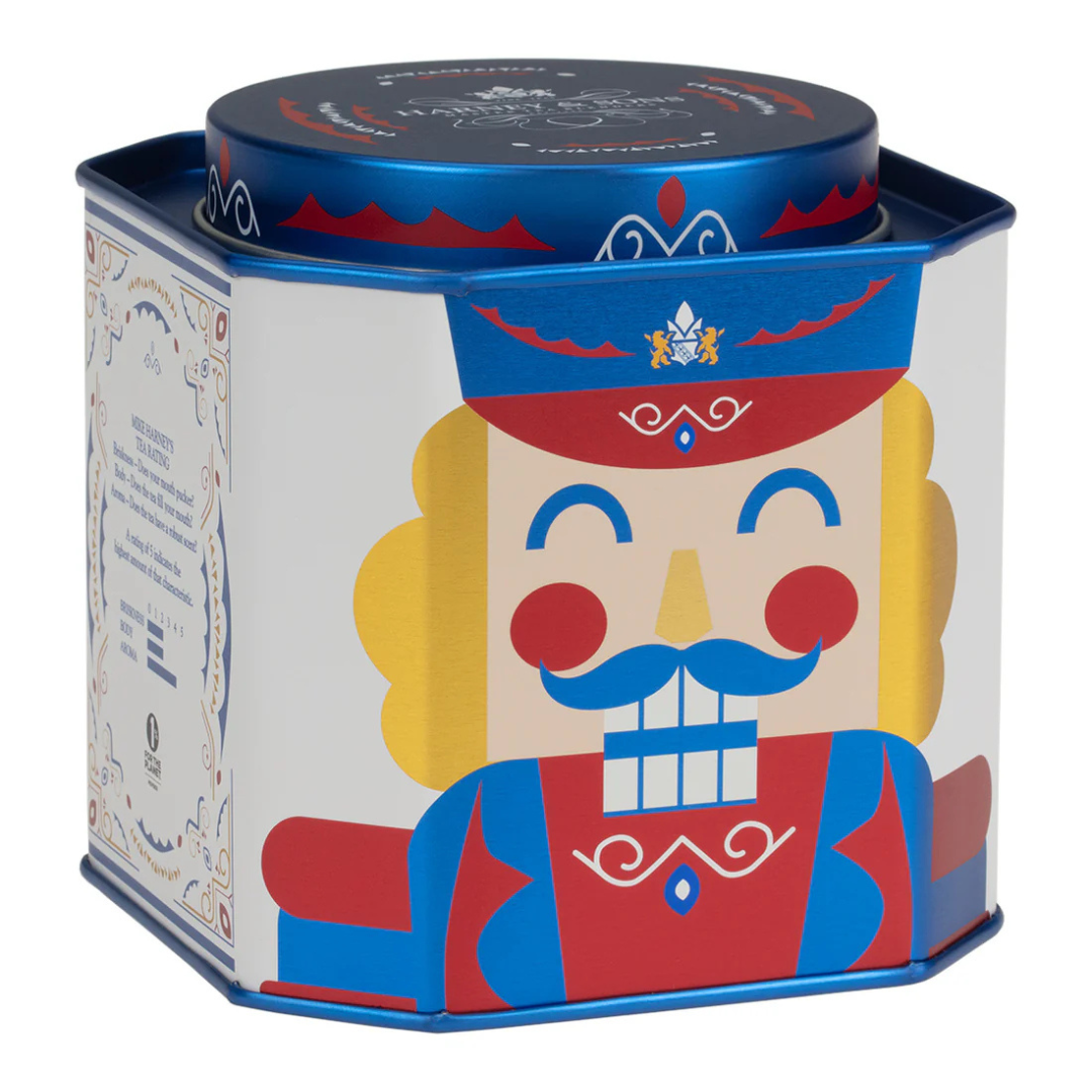 A decorative tin container with colorful nutcracker design featuring blue, red, and yellow accents.