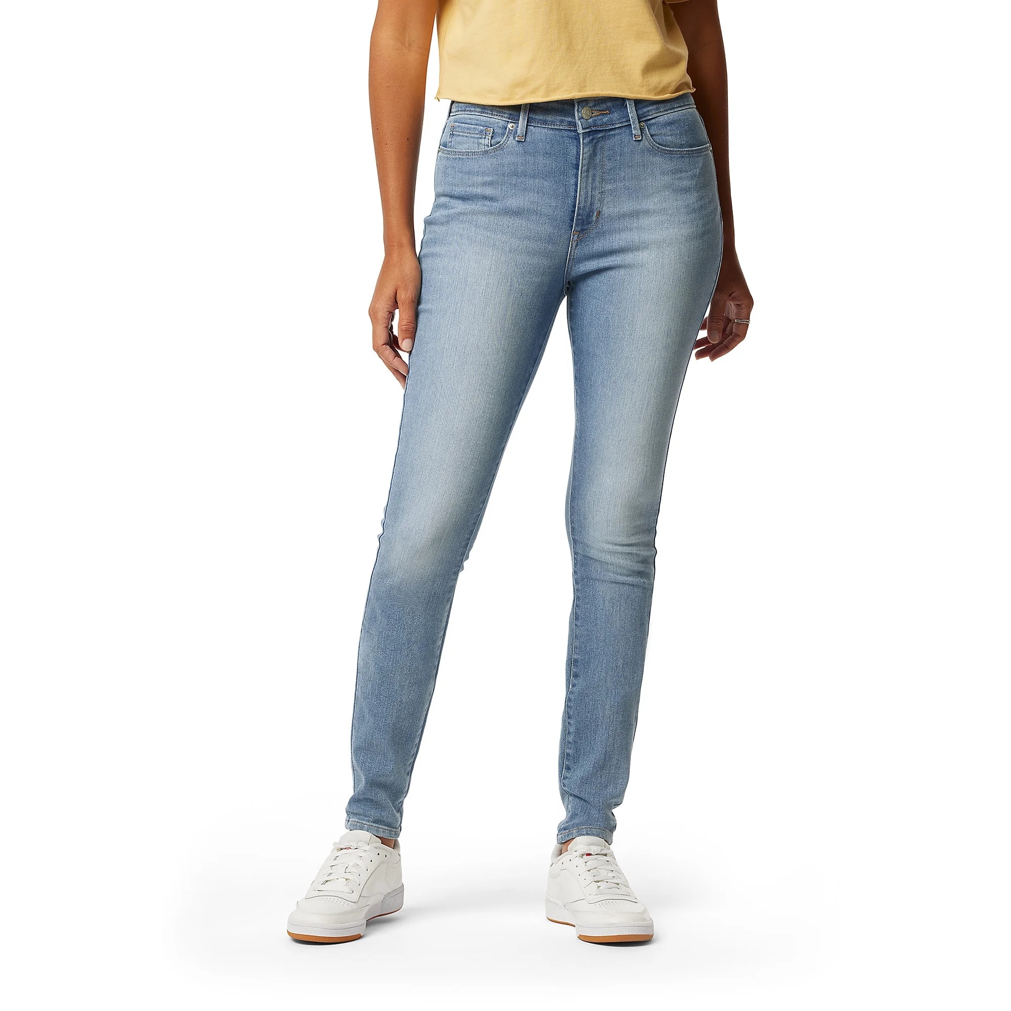 Levi Strauss Signature Skinny Jeans in light blue denim feature a high waist, a sleek, form-fitting design, and classic five-pocket styling. They are paired with white sneakers, offering a casual look.