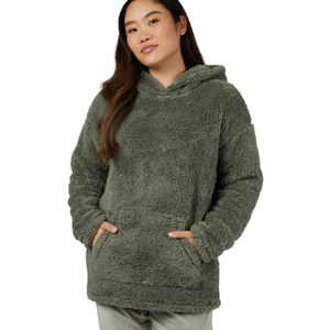 A person is wearing a cozy, oversized, olive-green sherpa hoodie with a large front pocket and hood.