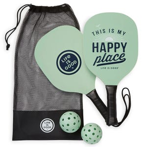Pickleball set with two mint green paddles and two perforated balls, featuring \“Life is Good\“ branding and a mesh carrying bag.