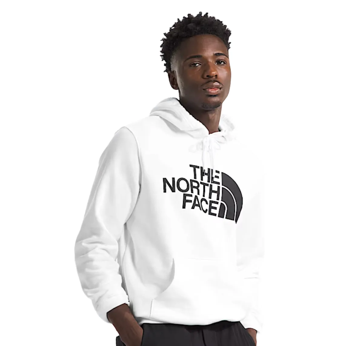 A man wears a white The North Face hoodie with a black logo, paired with dark pants.