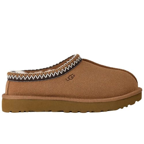 A tan slip-on clog with a thick sole, fur lining, and decorative trim, featuring the UGG logo.