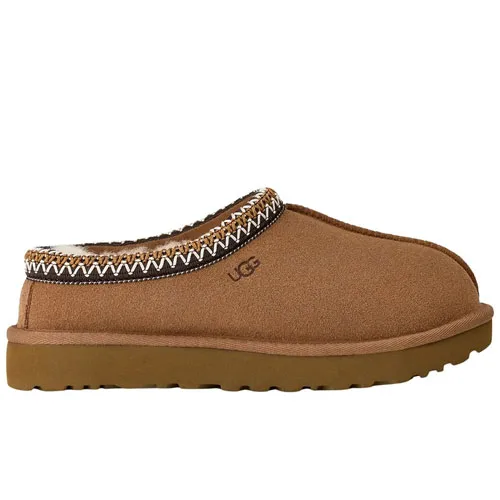 A tan slip-on clog with a thick sole, fur lining, and decorative trim, featuring the UGG logo.