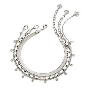 A silver necklace featuring multiple chain styles, including snake, curb, and cable chains, is adorned with small circular charms and delicate links terminating in geometric motifs.