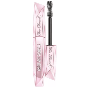 Too Faced Damn Girl! 24-Hour Mascara features a pink, diamond-shaped tube with a large hourglass brush for volumizing lashes. The packaging is embossed with the brand name and product name.