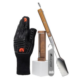 The MEATER Pro Bundle includes a wireless cooking thermometer with a wooden dock, a heat-resistant grilling glove, a stainless steel grilling tool, and a bottle opener.