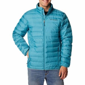 A man is wearing a blue, quilted Columbia Lake 22 Down Jacket with a zippered front, stand-up collar, and the Columbia logo on the left chest.