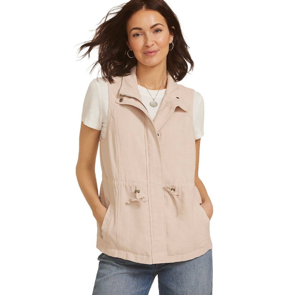 A woman wearing a light pink utility vest with a drawstring waist over a white T-shirt and jeans.