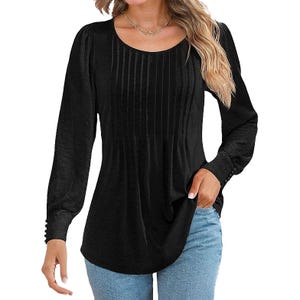 Black long-sleeve blouse with pleated front detailing, paired with light blue jeans.
