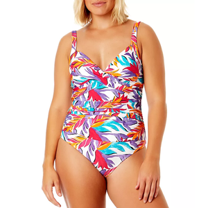 A woman wearing a colorful tropical print one-piece swimsuit with a V-neck and ruched midsection.