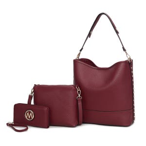A set of three burgundy bags: a large shoulder bag with a studded strap, a medium crossbody bag with a detachable strap, and a small wristlet wallet featuring a circular emblem.