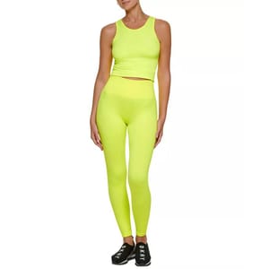Bright neon yellow high-waisted leggings paired with a matching crop tank top, featuring a seamless design for a snug fit, complemented by black sneakers labeled \“DKNY.\“