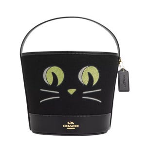 Black Coach bucket bag with a cat face design and a hanging brand tag.