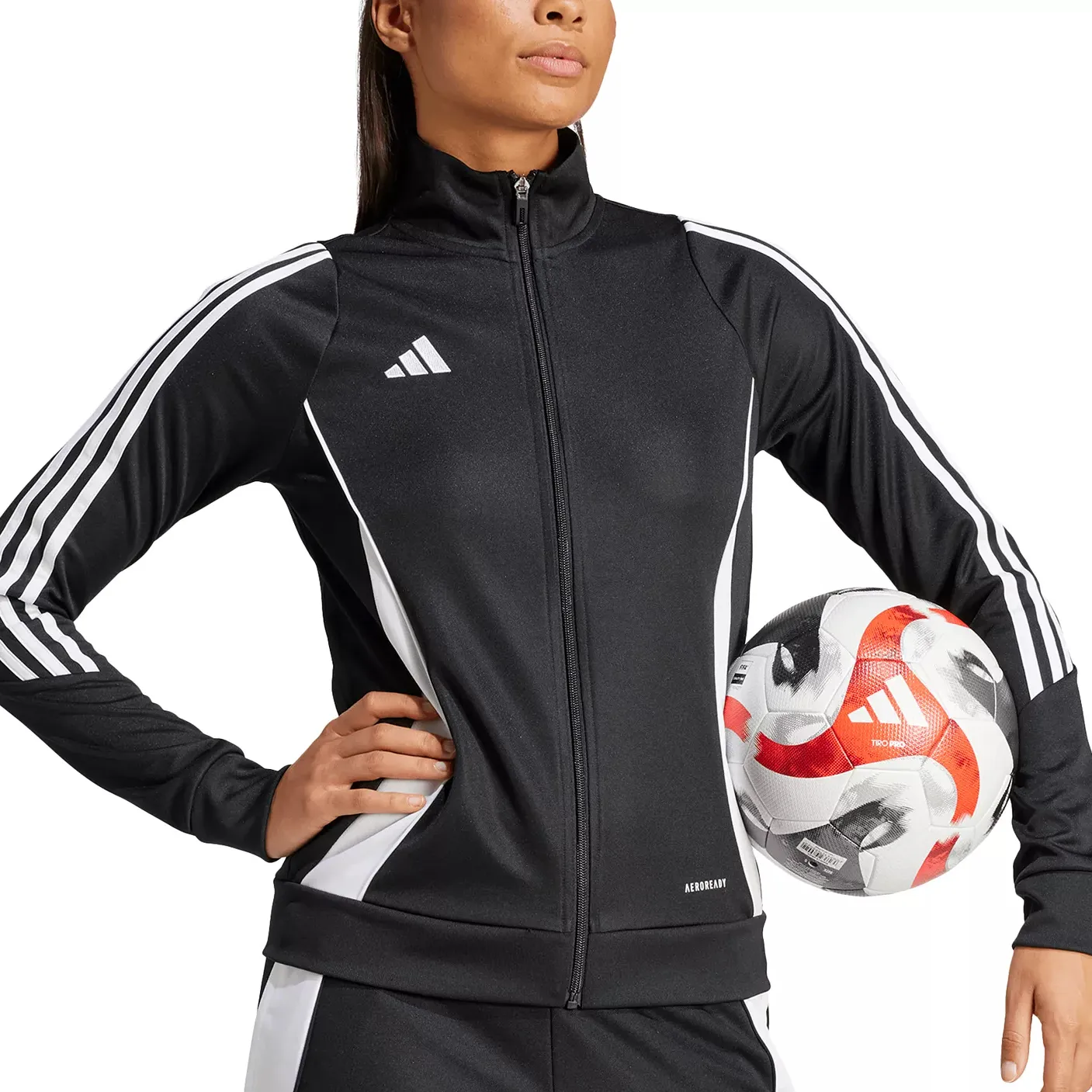A person wearing a black and white Adidas tracksuit holds a soccer ball. The tracksuit features the Adidas logo and Aeroready branding.