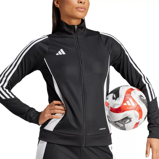 A person wearing a black and white Adidas tracksuit holds a soccer ball. The tracksuit features the Adidas logo and Aeroready branding.