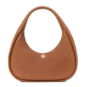 A Kate Spade Crescent Shoulder Bag in tan leather with a curved silhouette, featuring a simple gold Spade logo accent on the front. The bag has a top handle and a zip closure.