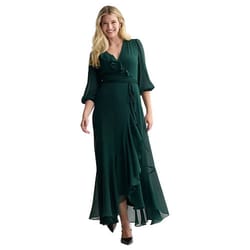 Woman wearing a dark green, long-sleeved, wrap-style dress with a V-neckline and ruffled hem, paired with black heels.