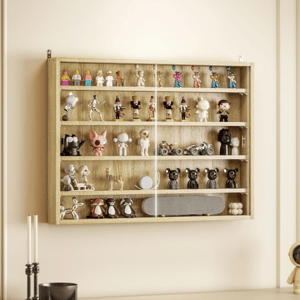A wooden wall-mounted display case holds various collectible figurines and toys, including animal figures, action characters, and mini bikes, with a glass front. Below, a light-colored cabinet features a candles, a bowl, and a space-themed figure.