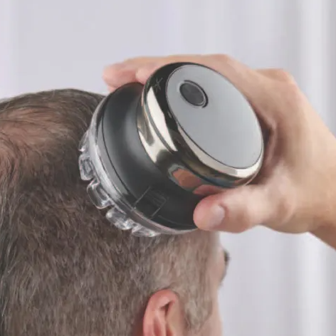 A handheld electric head shaver is being used on a man's head, designed for convenient and quick hair trimming.