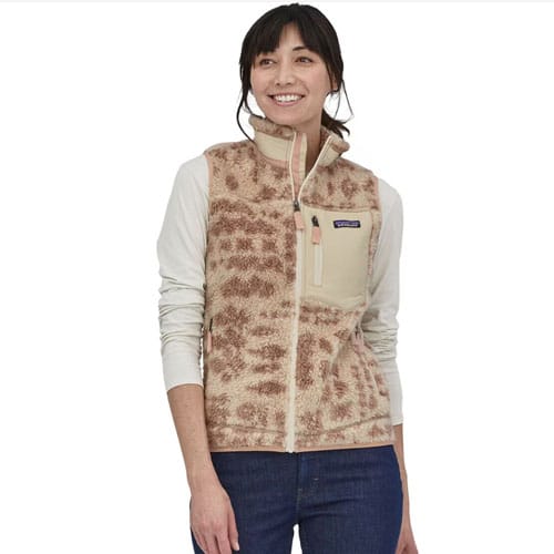 A woman is wearing a beige fleece vest with a pattern resembling animal print and a contrasting vertical chest pocket.
