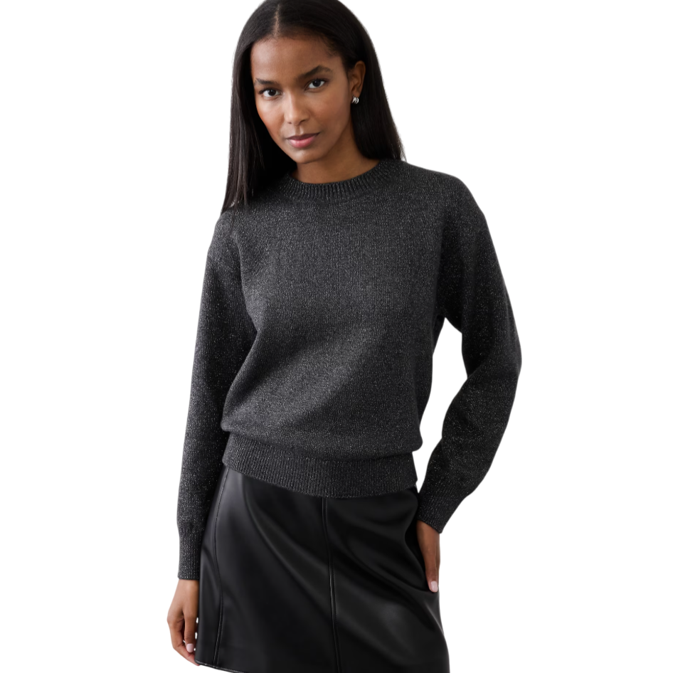 A woman is wearing a sparkly dark gray sweater paired with a black leather skirt, standing against a plain background.