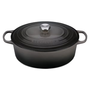 Le Creuset oval cast iron Dutch oven with a dark finish and metallic knob. Features side handles and the Le Creuset branding on the lid.