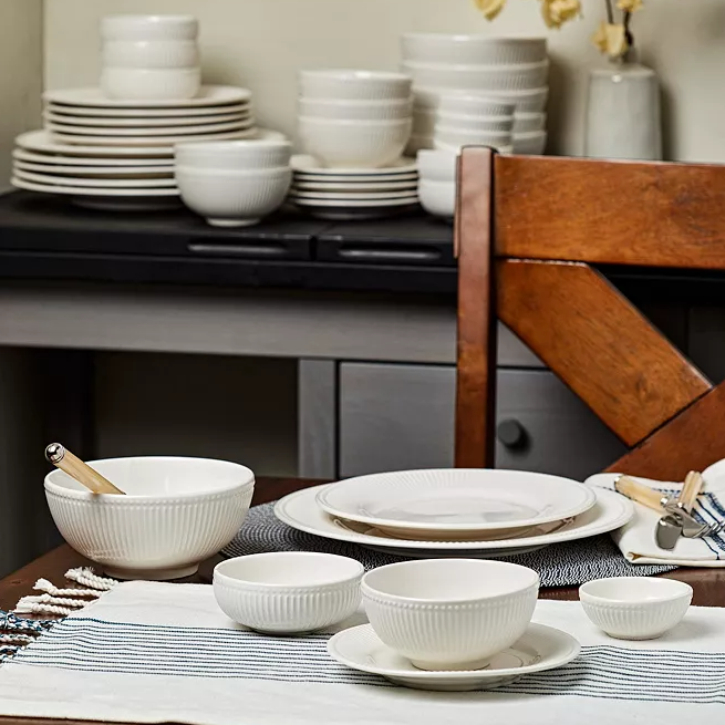 A set of white dinnerware including plates, bowls, and saucers displayed on a table.