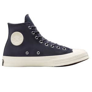 A high-top navy blue sneaker with a white rubber sole, featuring a classic Converse design with a circular logo patch on the ankle.